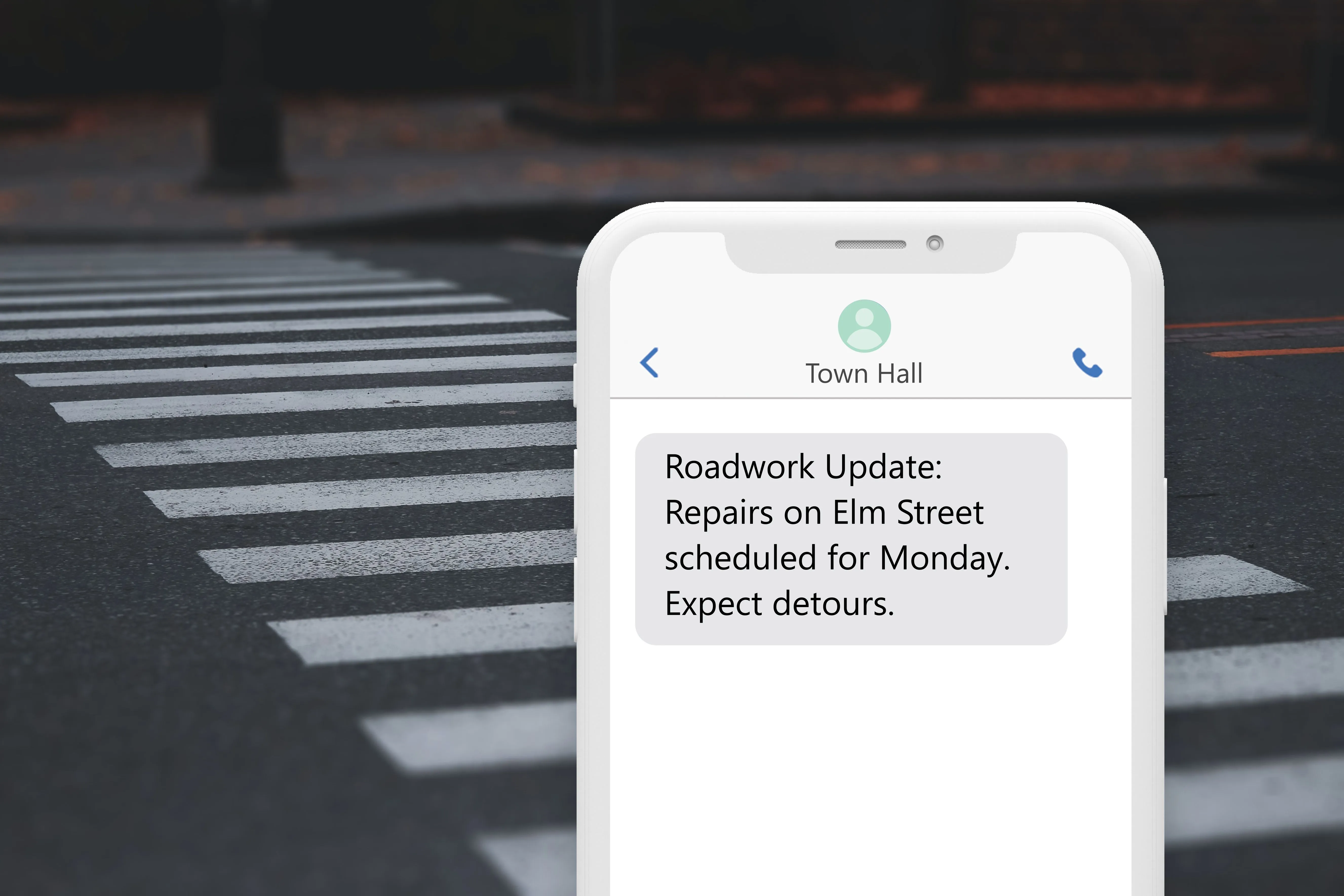 a phone showing a message from town hall alerting of roadwork with a crosswalk in the background